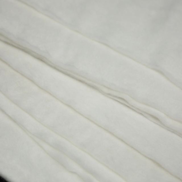 White polypropylene nonwoven filament geotextile close-up, showing uniform fiber structure and edge detail for civil engineering applications