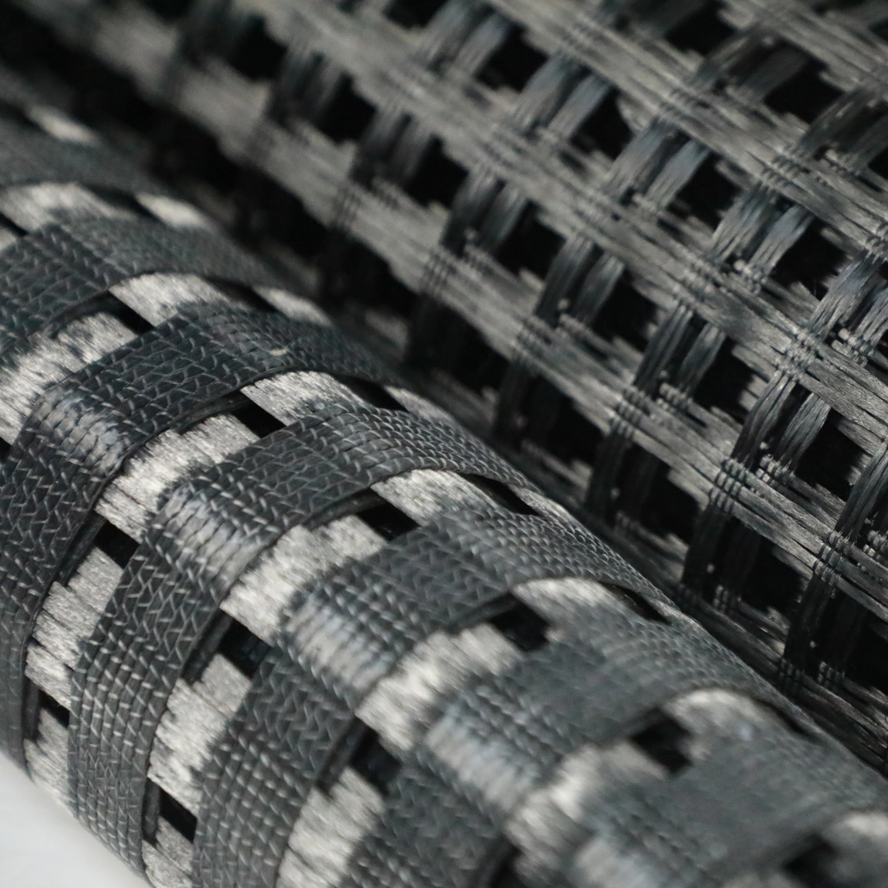 Close-up of warp-knitted fiberglass geogrid structure, showing high-density mesh for soil stabilization
