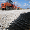 HDPE geocell with gravel infill for road base stabilization, installed with motor grader on construction site