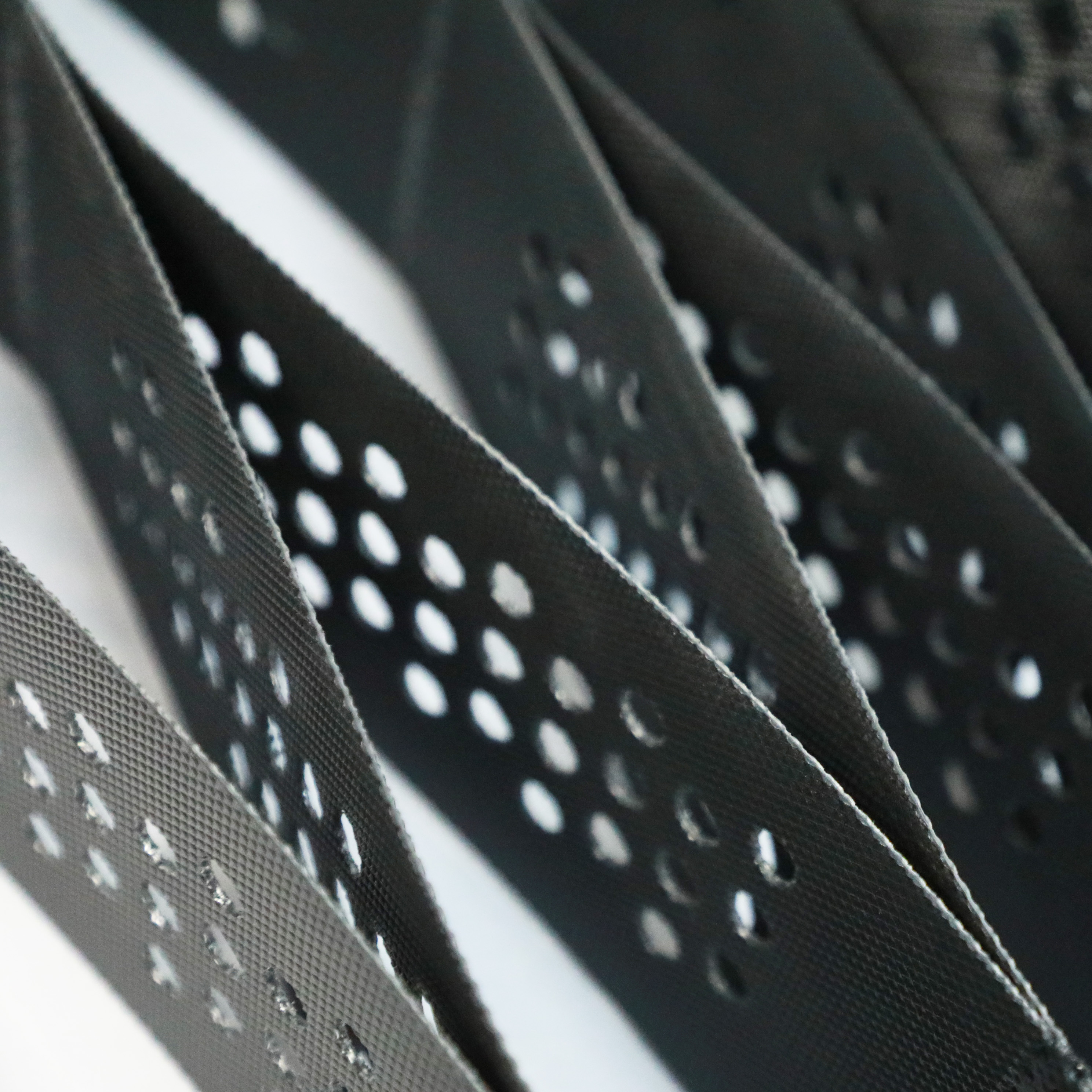 Close-up of Zhongloo black perforated HDPE geocell sheets showing drainage holes
