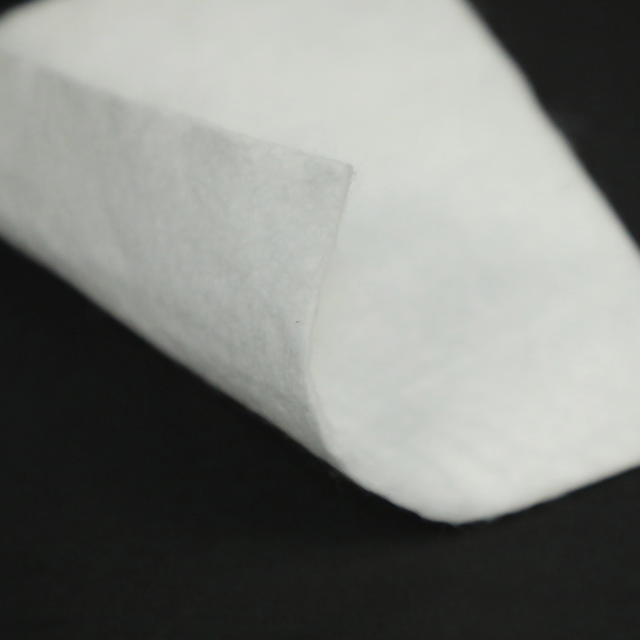 White polypropylene nonwoven filament geotextile close-up, showing uniform fiber structure and edge detail for civil engineering applications